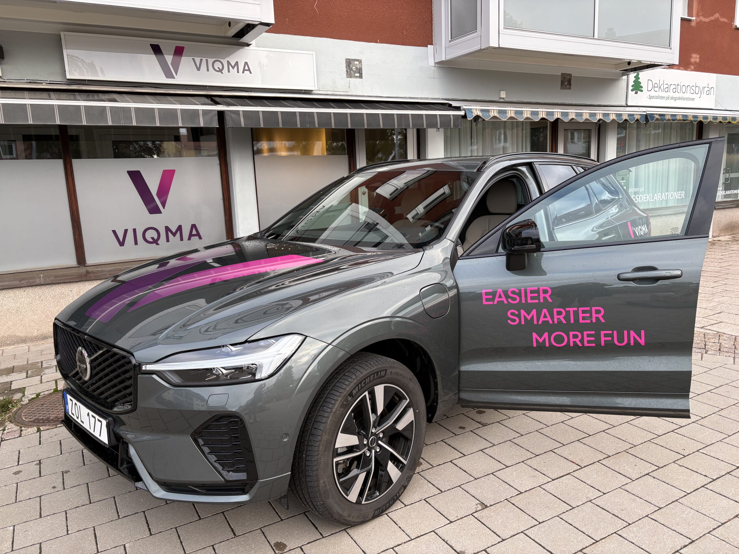 VIQMA-profilerad bil framför VIQMAs kontor med texten Easier, Smarter, More Fun på bildörren.